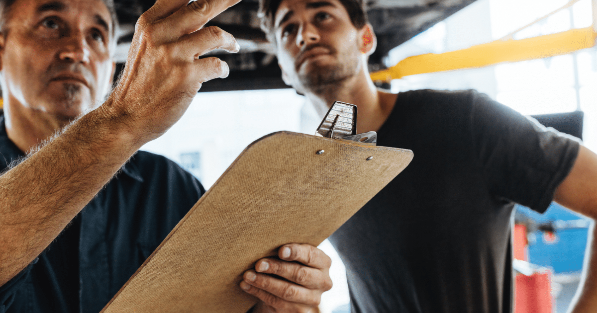 Two men reviewing checklist on clipboard.