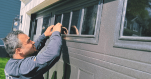 Man repairs window on garage door panel.
